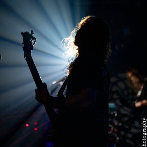Bass player in silhouette against a spotlight at Club 85