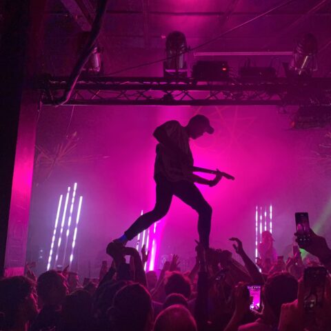 Guitarist silhouetted in pink light at Club 85