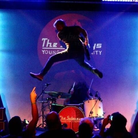 Singer mid jump on the Club 85 stage
